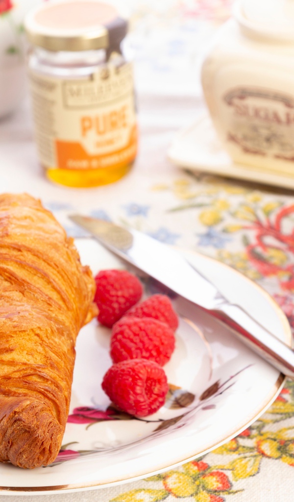 Круассан на тарелке со свежей малиной