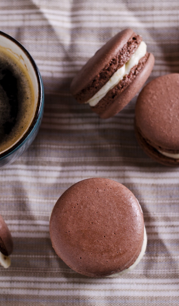 Чашка кофе на столе с десертом макарун и будильником