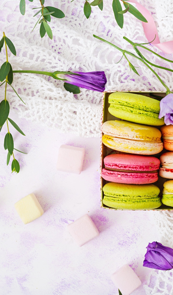 Десерт макарон на столе с кружевной салфеткой и маршмеллоу