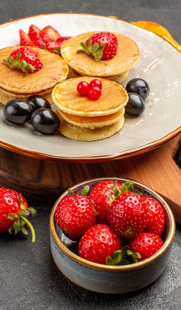 Оладьи с виноградом и клубникой на тарелке 