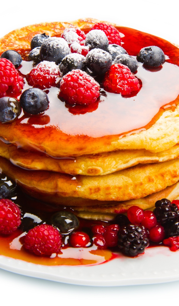 Оладьи с медом и ягодами малины и черники на белом фоне