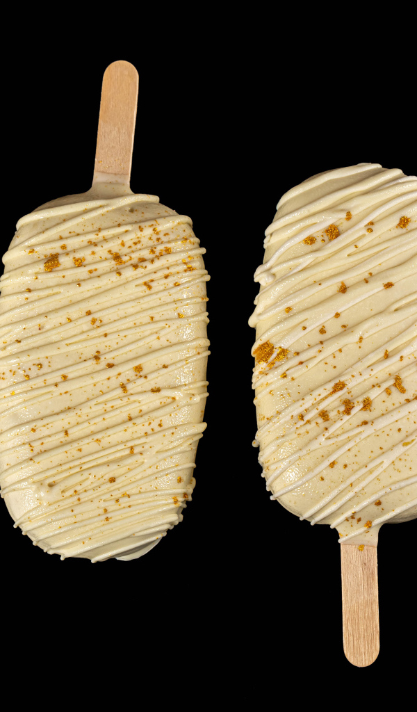 Мороженое на палочке в белом шоколаде на черном фоне