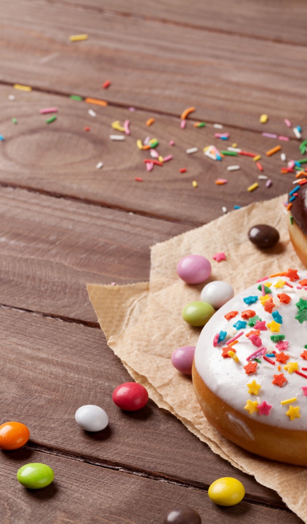 Сладкие пончики с глазурью на столе с конфетами