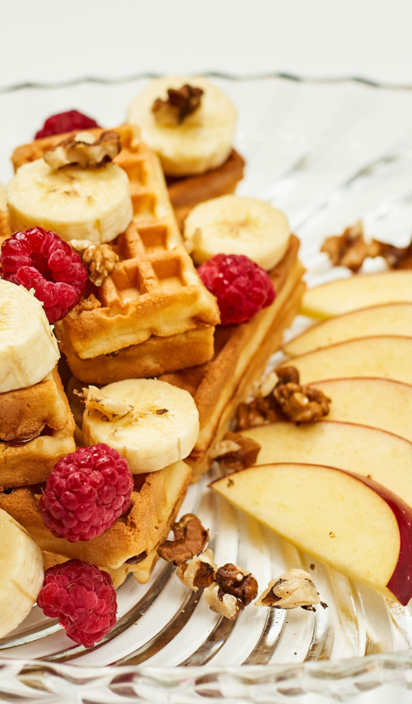 Сладкие вафли на тарелке с бананом, малиной и яблоком