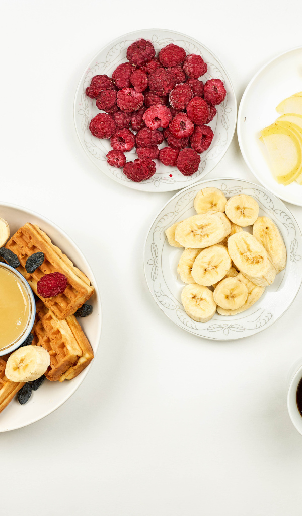 Сладкие вафли с малиной и бананами на столе  с кофе