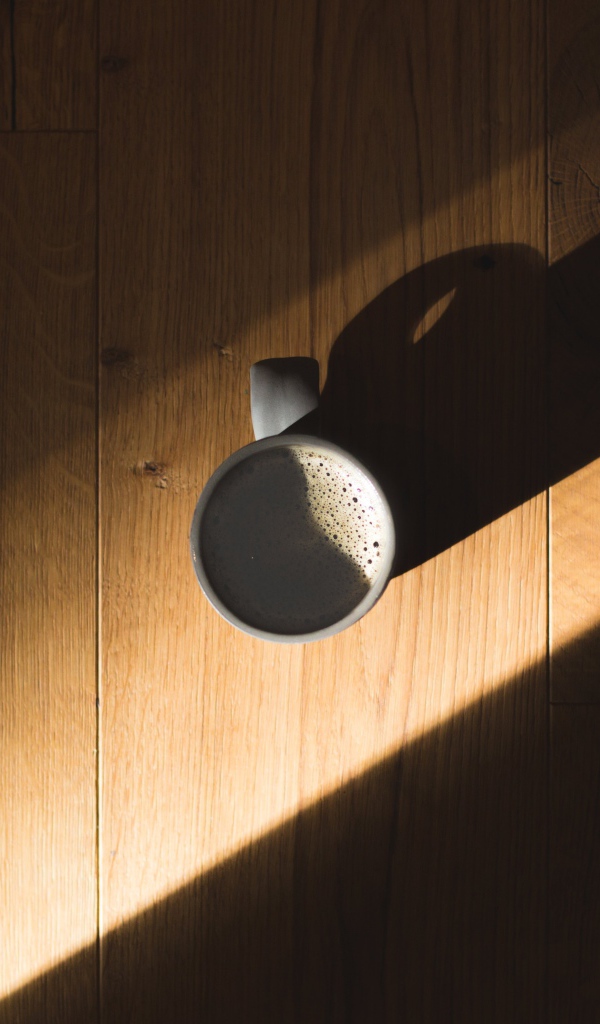 Чашка кофе стоит на столе в лучах солнца
