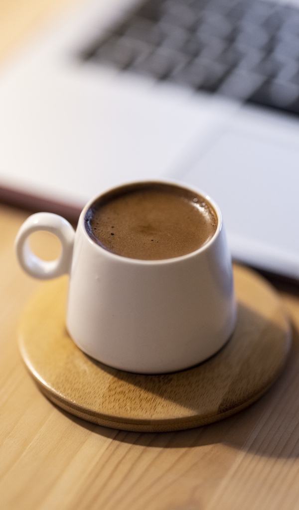 Чашка кофе стоит у ноутбука 