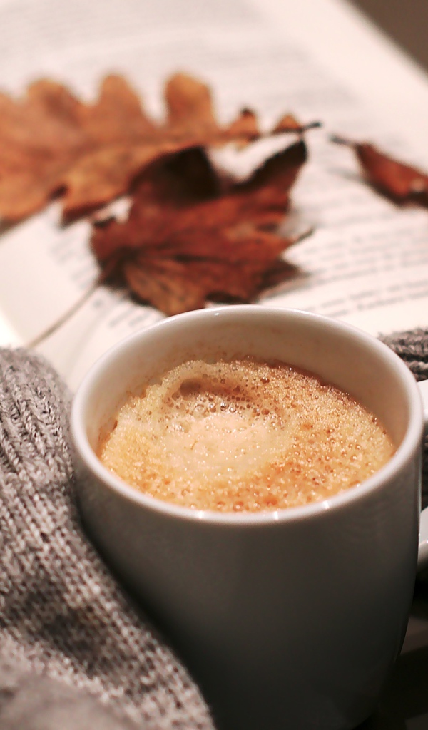 Чашка горячего кофе на столе с книгой 