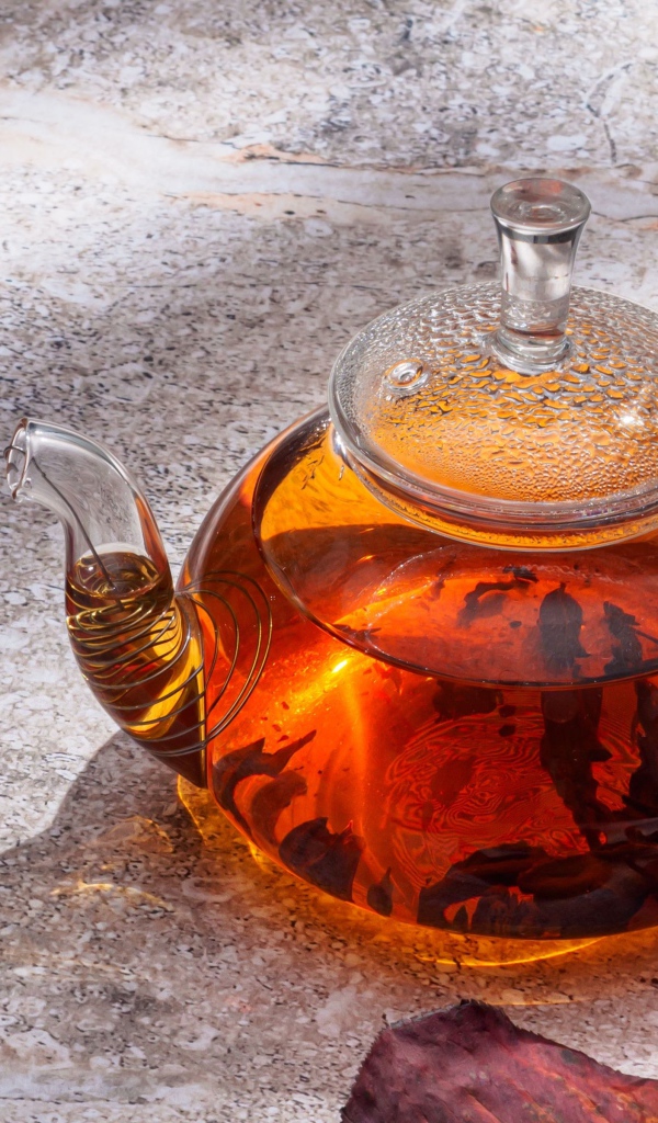 Стеклянный чайник на столе с листьями