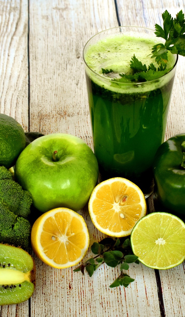 Зеленый свежий смузи на столе с овощами и фруктами 