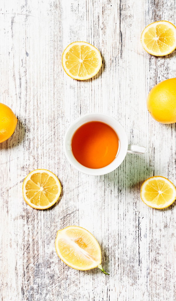 Желтые лимоны с чаем на белом столе 