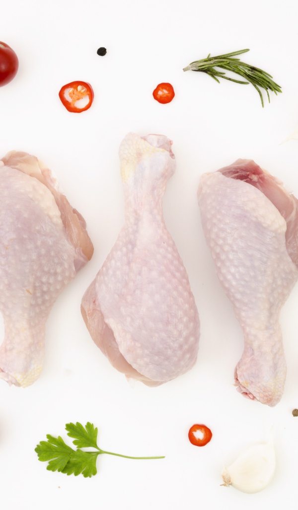 Свежие куриные бедра с перцем и помидорами на белом фоне 