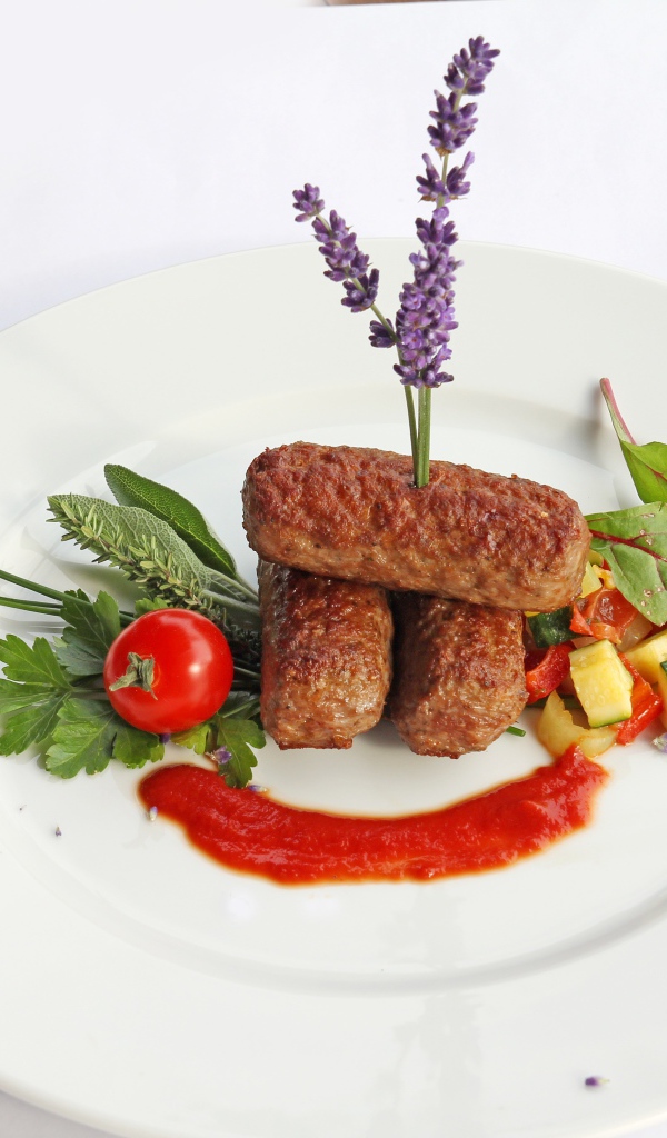 Meat sticks on a plate with herbs and sauce