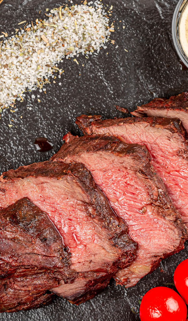 Мясо с помидорами и соусами на доске 