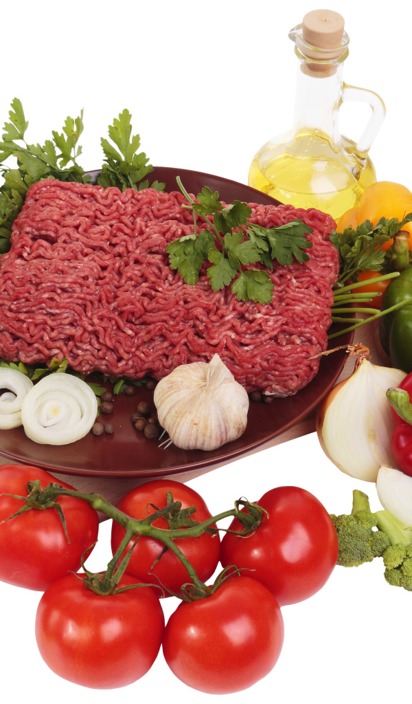 Minced meat on a white plate with vegetables and herbs