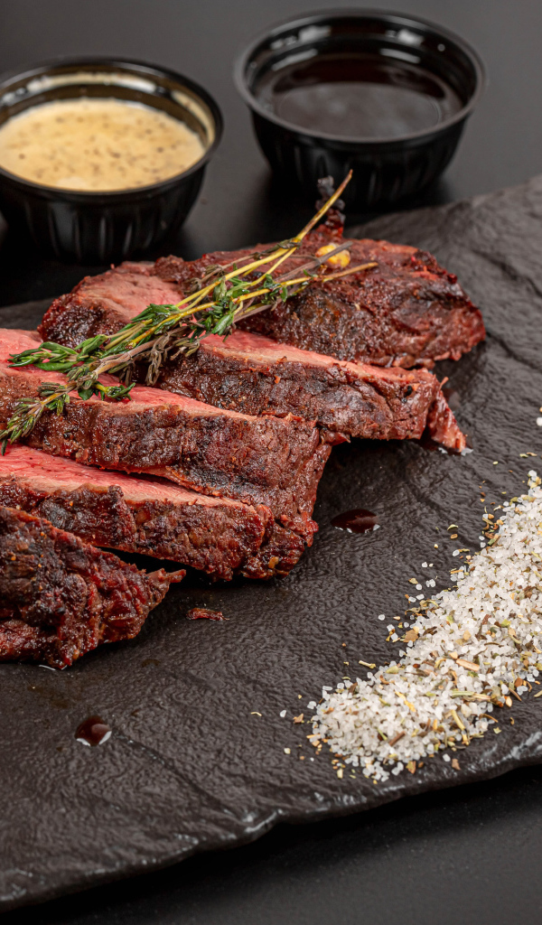 Кусок запеченного мяса на доске с кукурузой и специями 