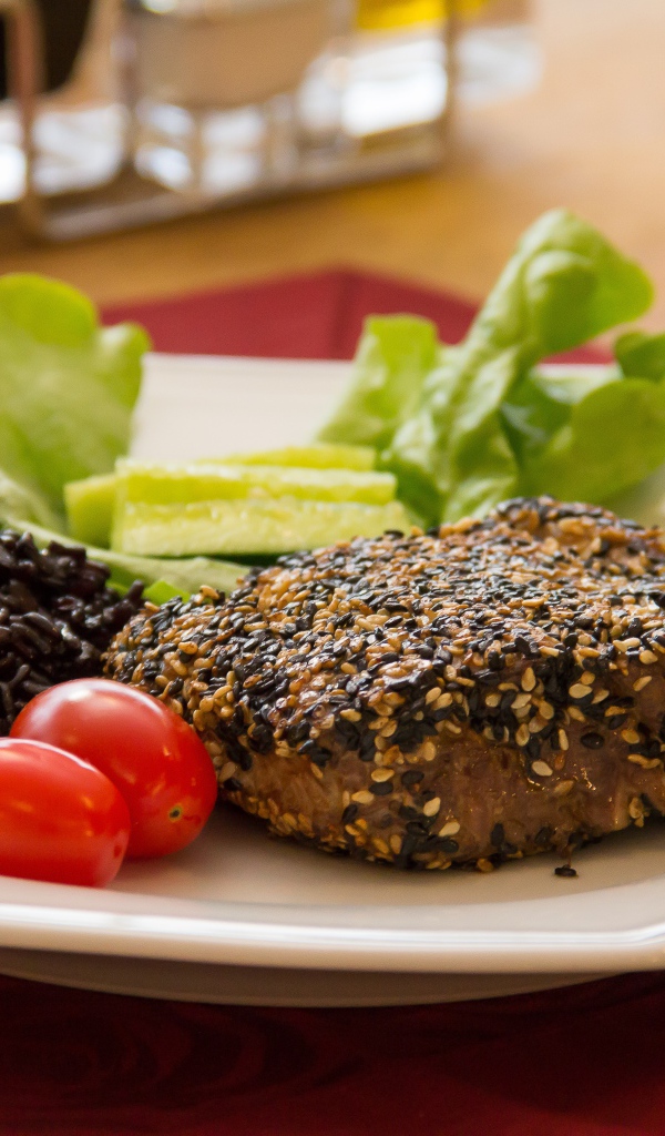 Кусок мяса на тарелке с рисом и овощами 