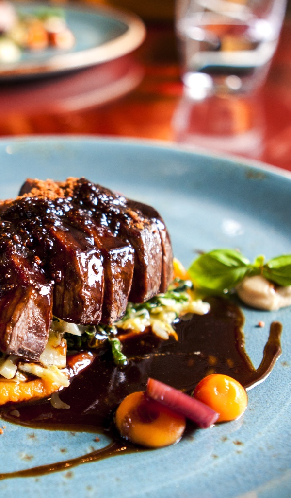 Кусок мяса с соусом на тарелке в ресторане