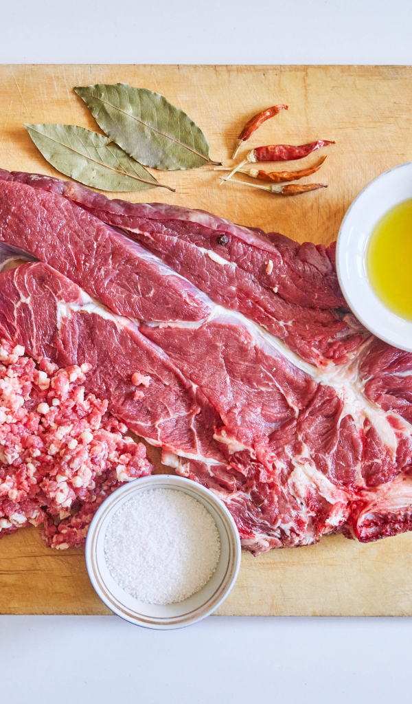 Кусок мяса со специями и оливковым маслом на доске 