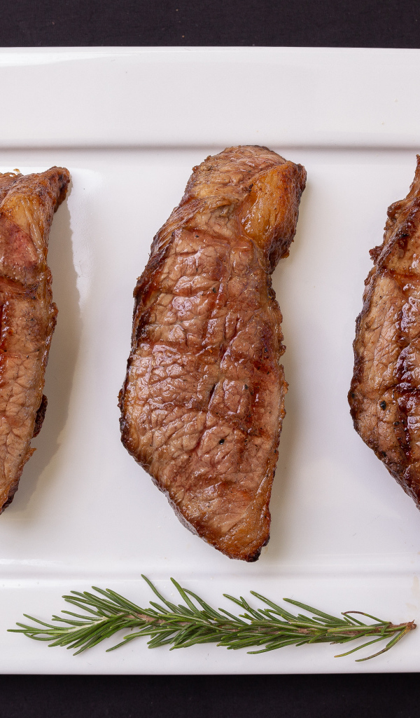 Три куска жареного мяса на большой белой тарелке