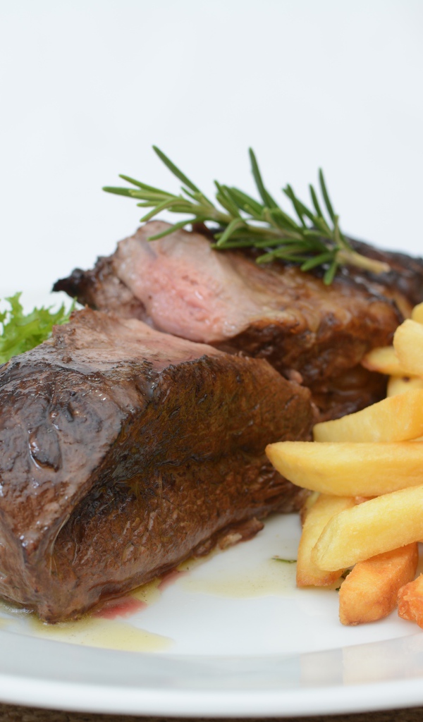 Два куска мяса на тарелке с картофелем фри 