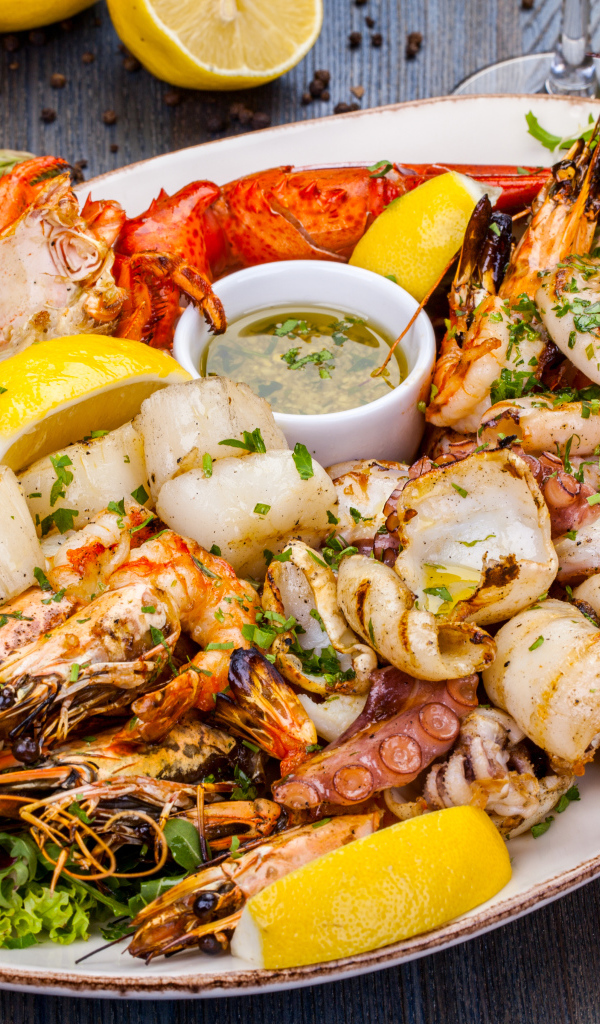 Запеченные морепродукты на тарелке с лимоном 