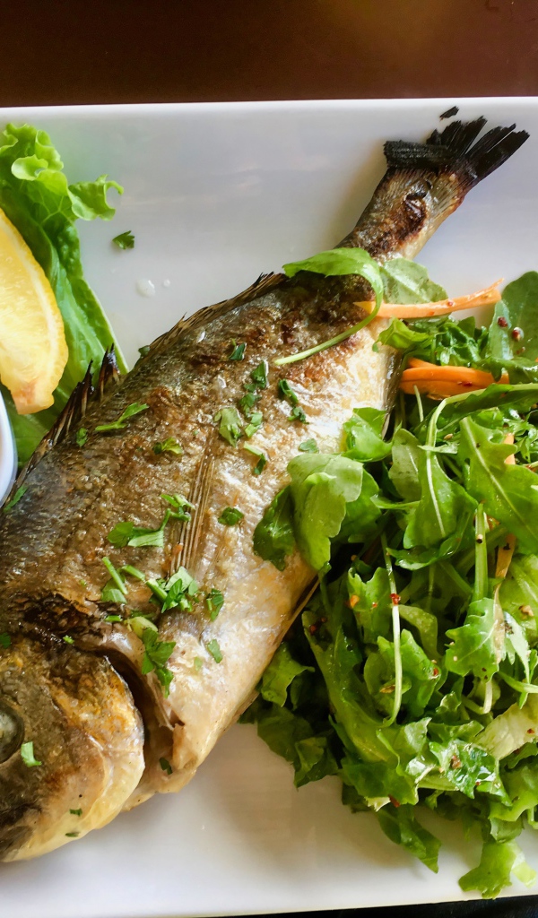 Жареный карась на тарелке с салатом 