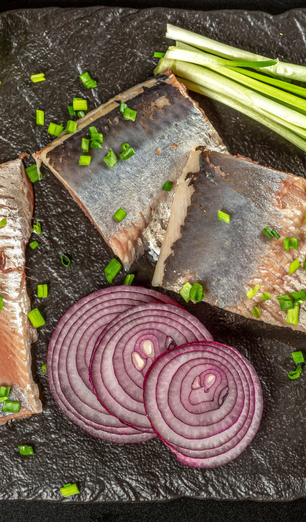 Куски сельди с луком и кусочками лимона