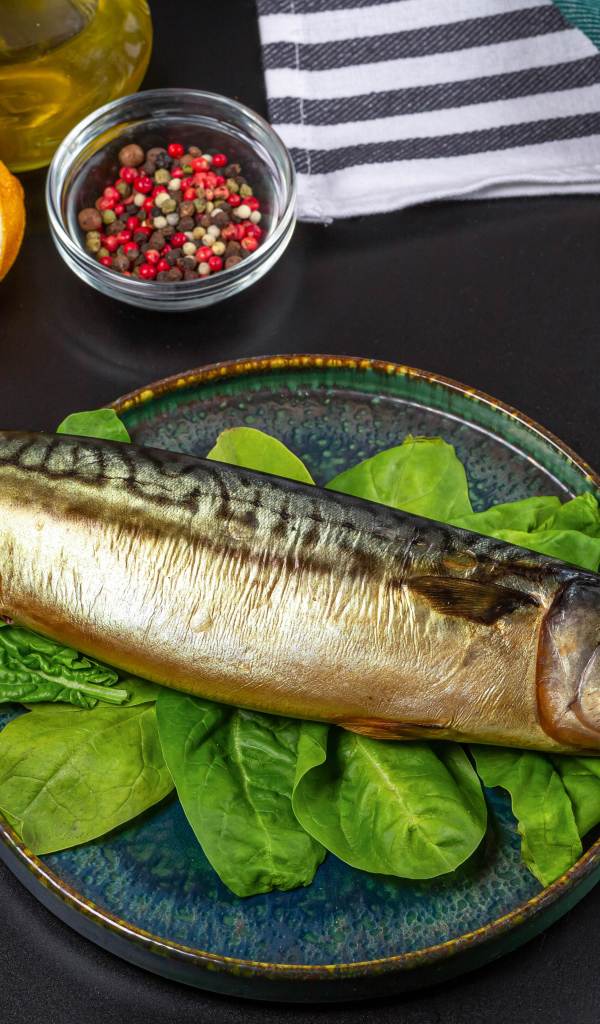 Большая копченая скумбрия на тарелке с базиликом