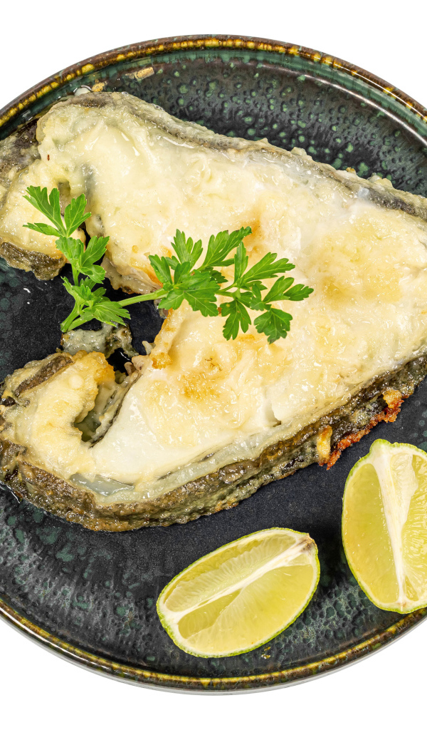 Кусок рыбы на тарелке с лимоном на белом фоне