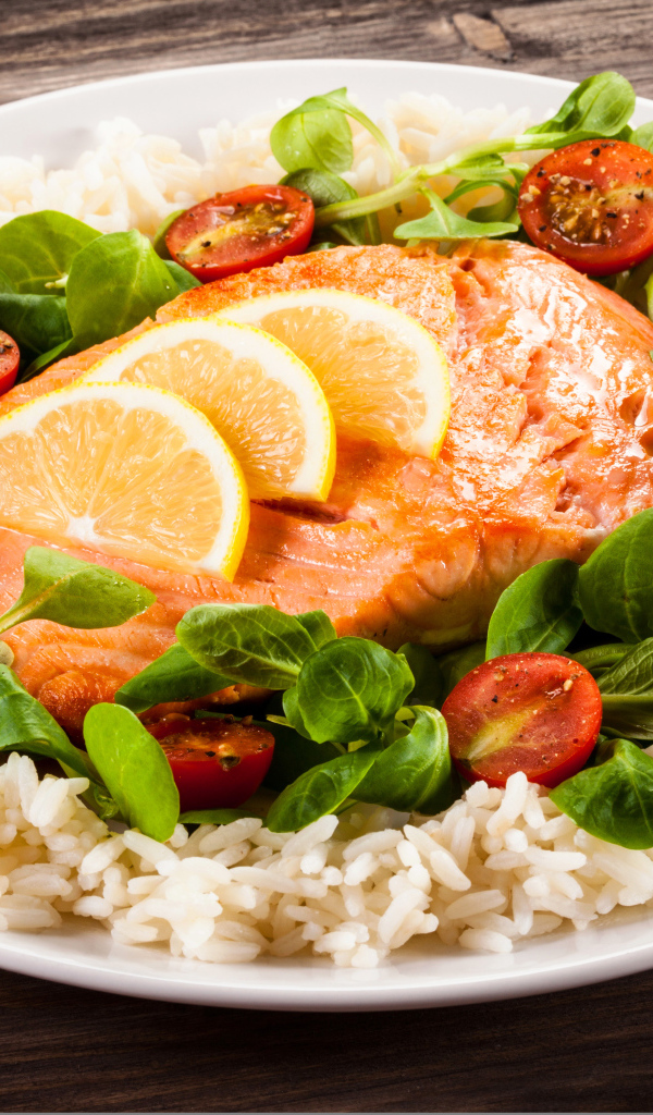 Кусок рыбы на тарелке с помидорами, рисом и листьями базилика 