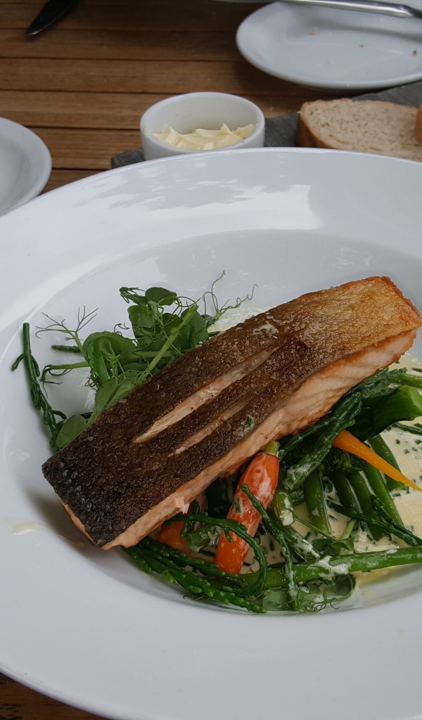 Кусок красной рыбы с овощами на столе в ресторане