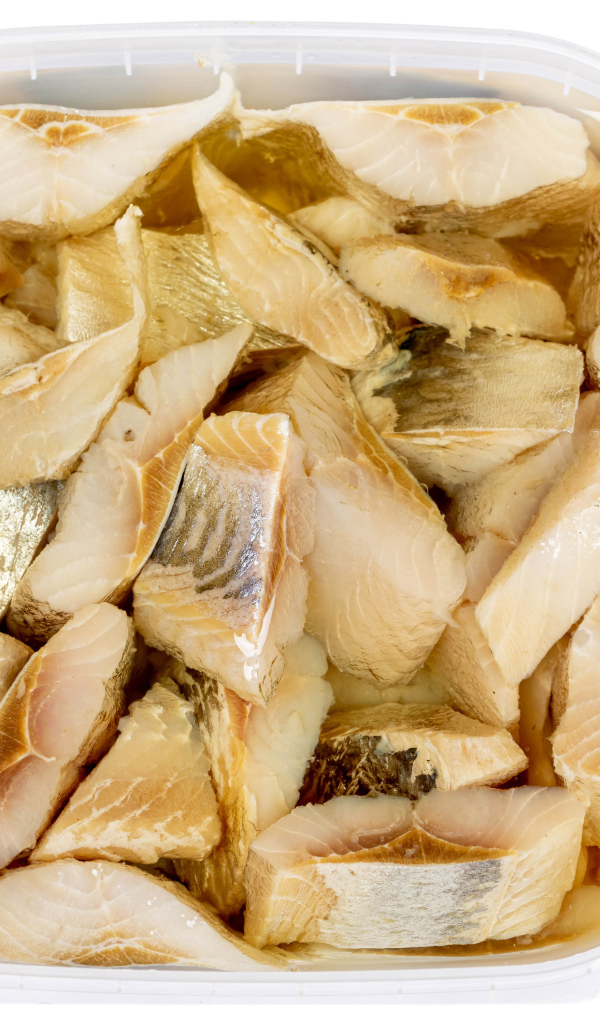 Pieces of herring in a jar with butter on a white background