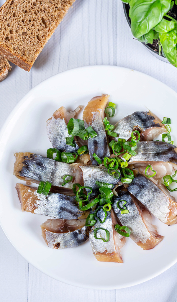 Куски скумбрии на столе с луком, хлебом и базиликом