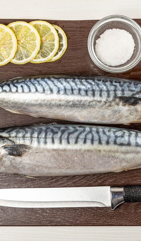 Две свежие скумбрии на доске с лимоном 