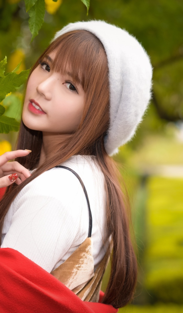 Девушка в берете стоит у куста с желтыми цветами