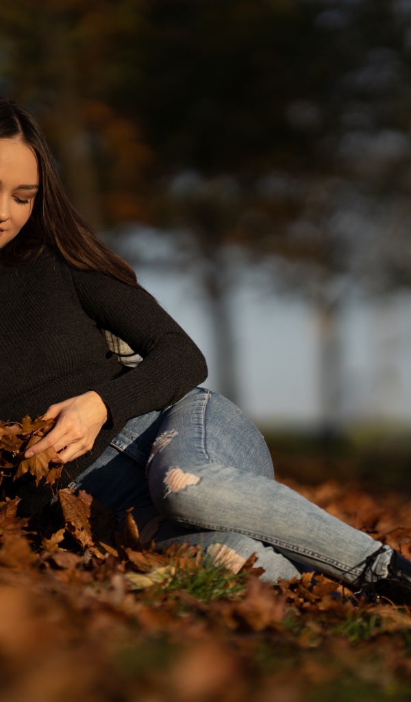 Молодая девушка лежит на опавшей листве