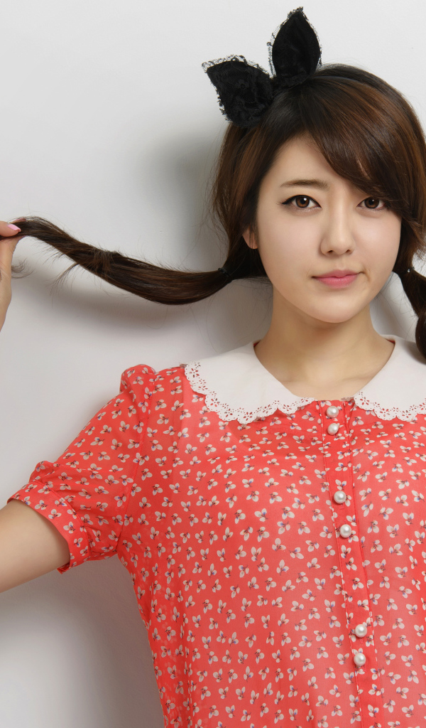 Девушка азиатка в платье стоит у стены 