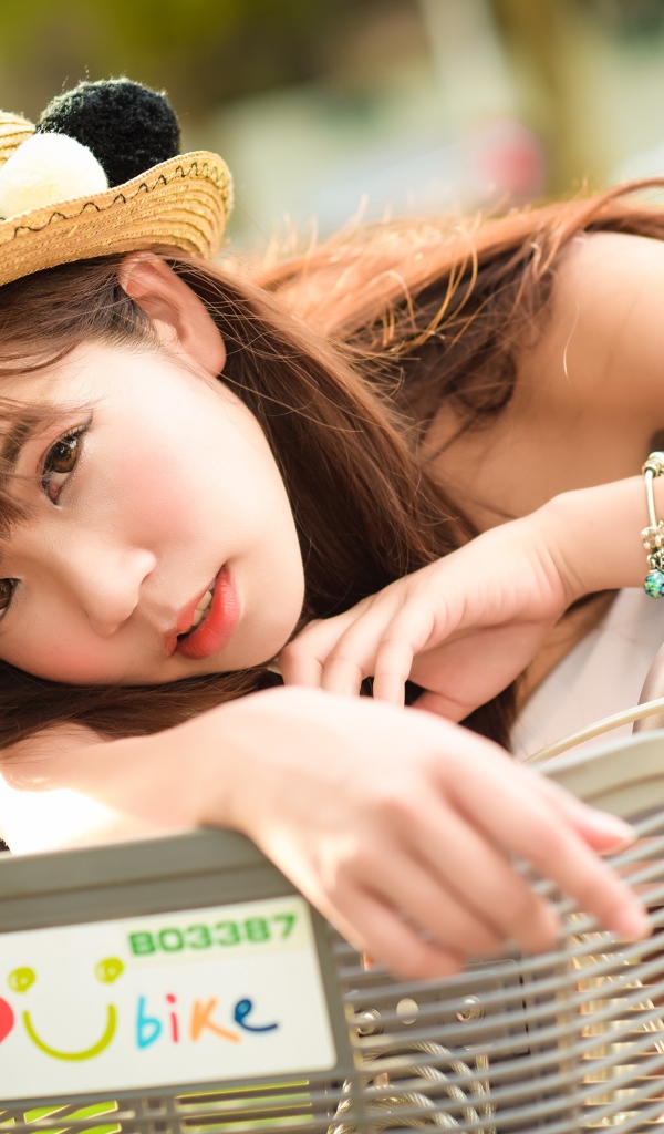 Девушка азиатка в шляпке на велосипеде 