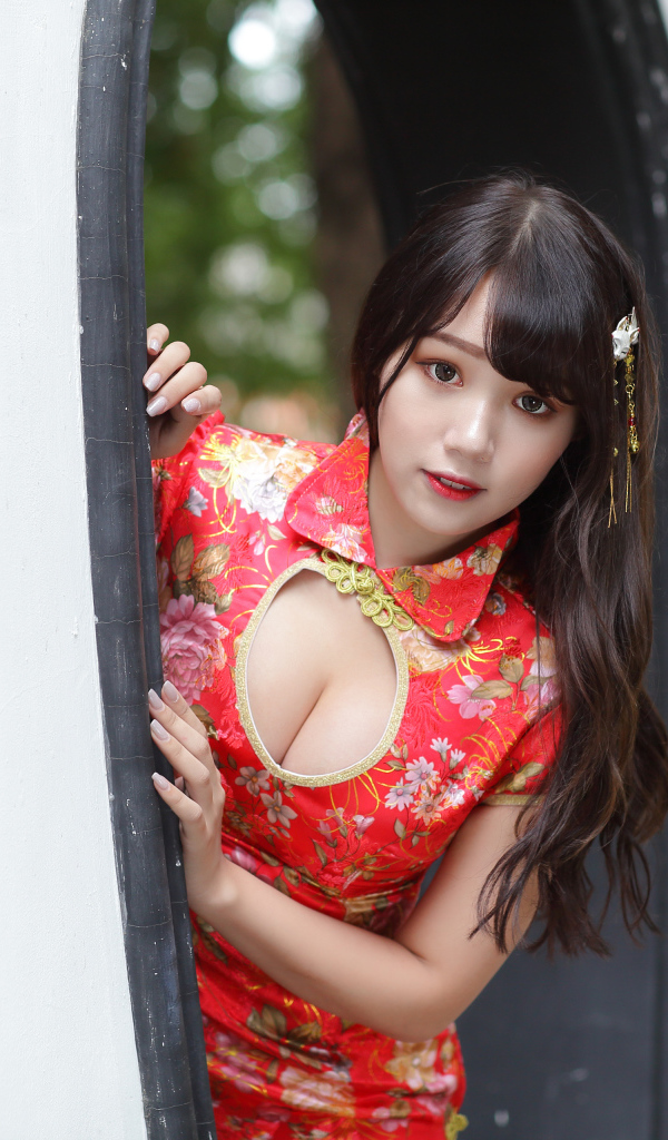 Девушка азиатка в красном платье стоит в арке