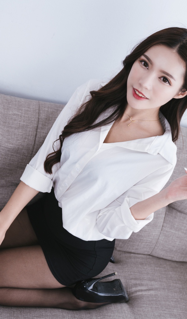 Девушка азиатка в белой рубашке на диване 