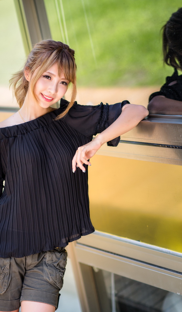 Девушка азиатка в черной блузке у окна