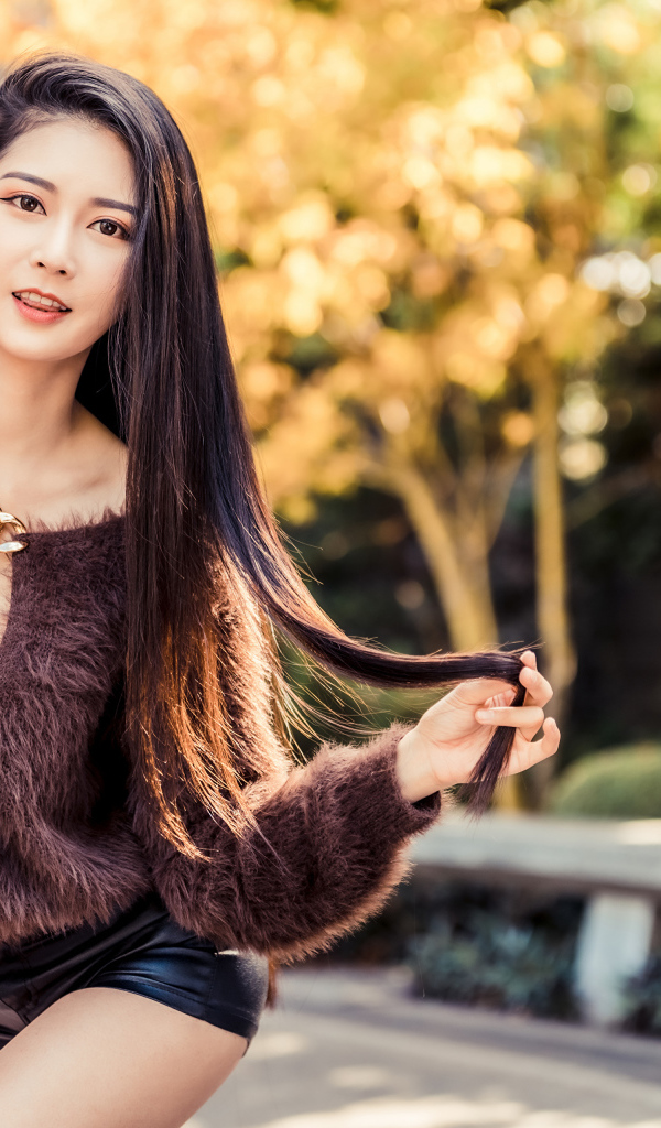 Девушка азиатка в черных шортах у стены