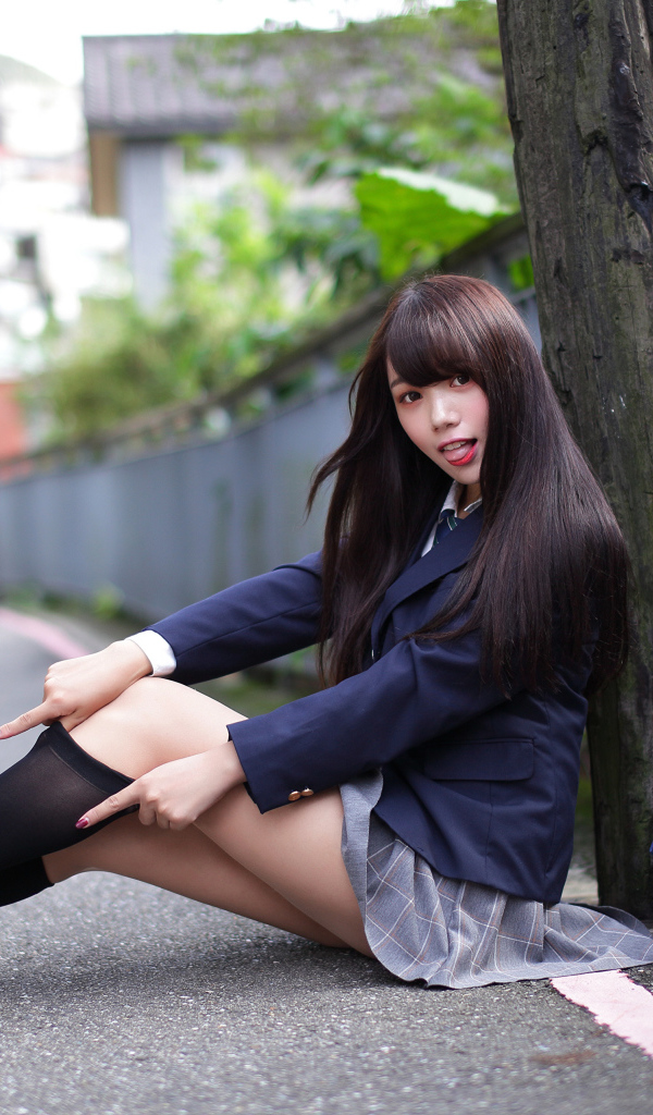 Девушка азиатка в черных чулках сидит у дерева