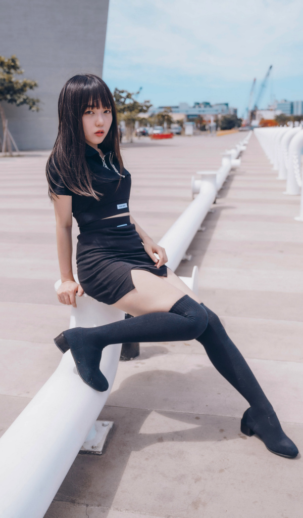 Девушка азиатка в черном костюме на пристани 