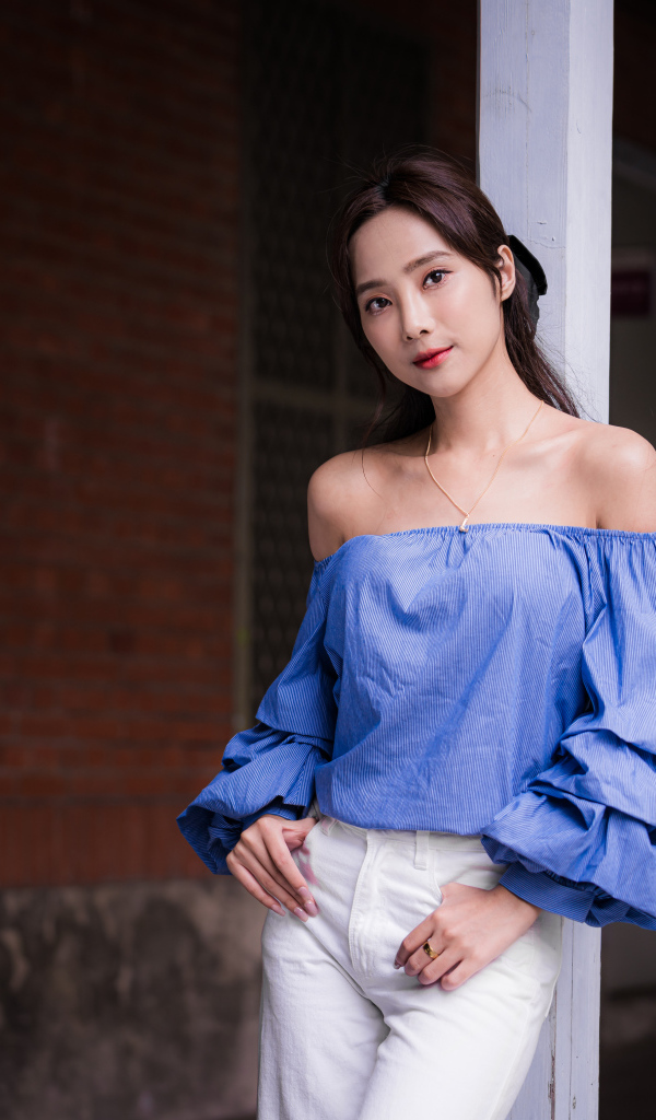 Девушка азиатка в белых брюках у дома