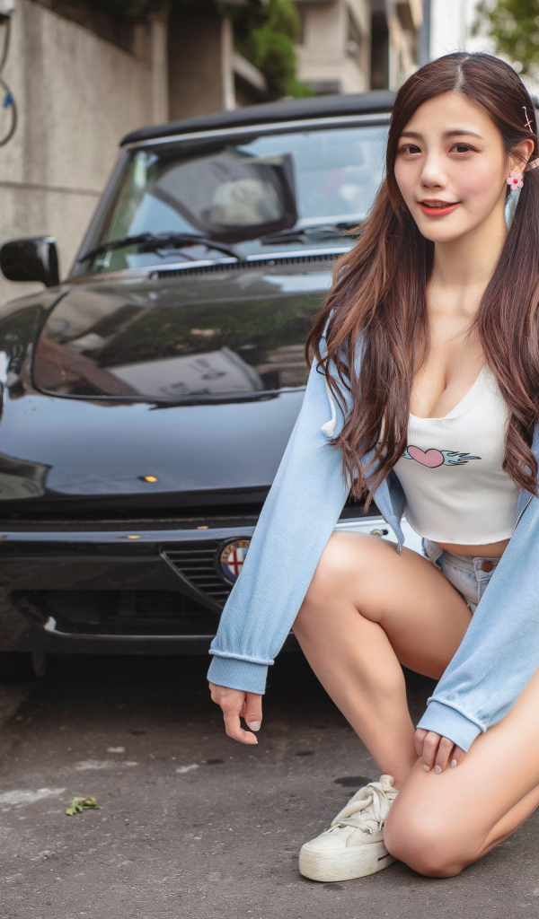 Девушка азиатка сидит возле машины 