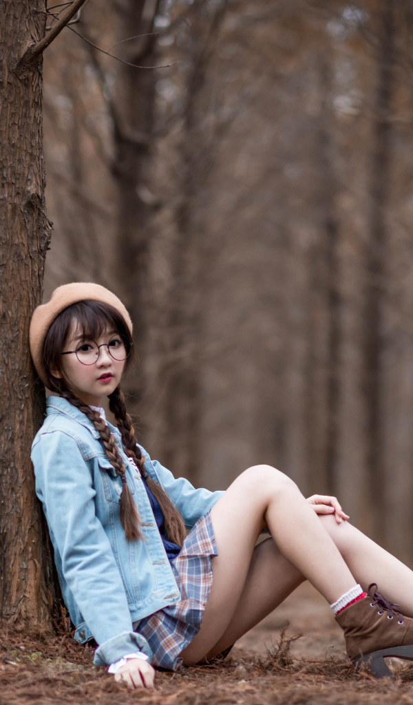 Девушка азиатка школьница сидит под деревом