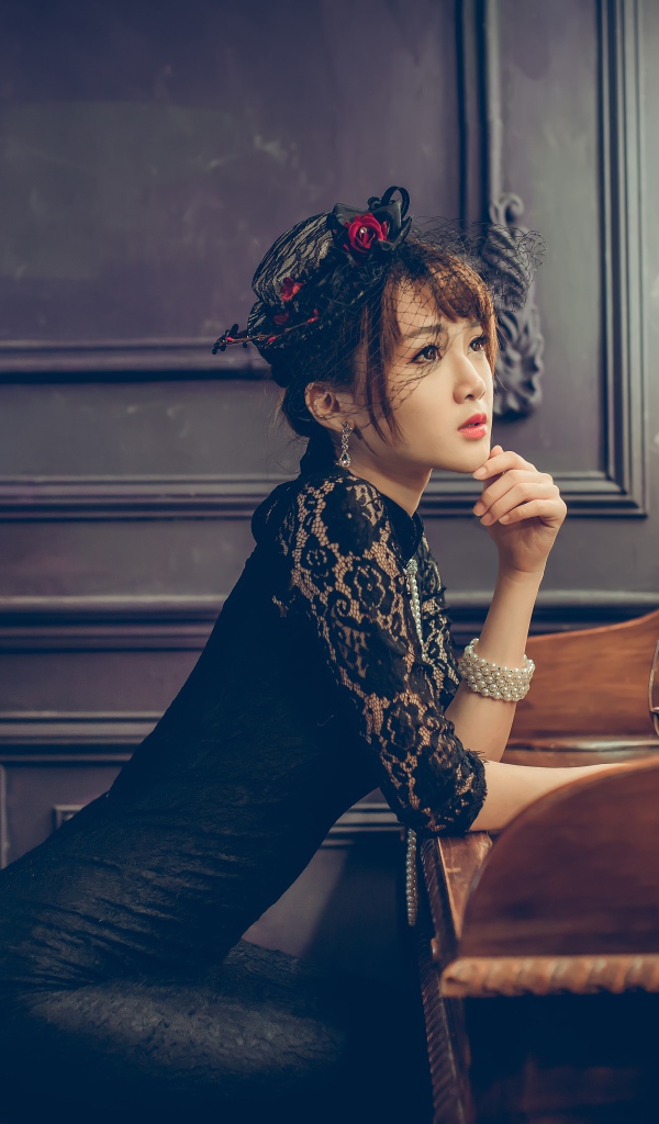Красивая девушка азиатка в черном платье сидит в кафе
