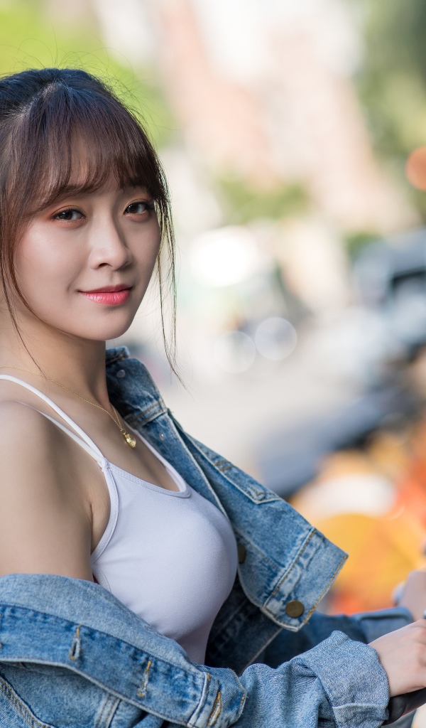 Красивая азиатка в джинсовой куртке с велосипедом